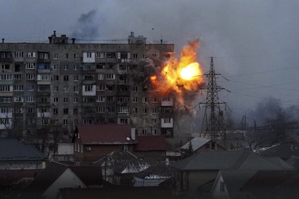 An explosion is seen in an apartment building after Russian’s army tank fires in Mariupol, Ukraine, on Friday.
