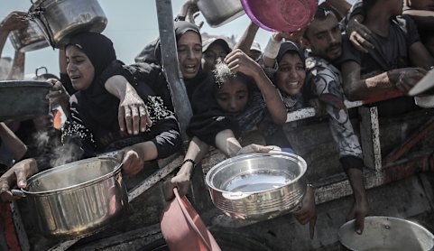 Palestinians try to collect free food from a charity kitchen in Gaza City this month.