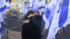 Two people embrace amid a sea of Israeli flags in hostages square in Tel Aviv.
