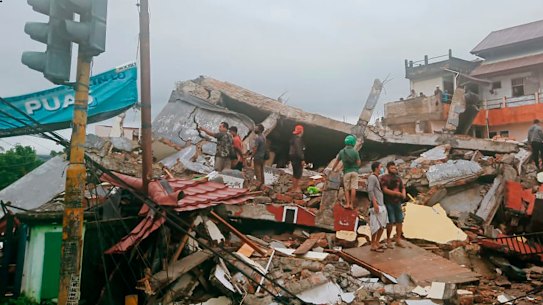 Residents inspect earthquake-damaged buildings in Mamuju, West Sulawesi, Indonesia, on Friday.