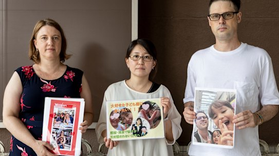 Catherine Henderson, Izumi Dobashi and Scott MacIntyre hold photos up of their children. 
