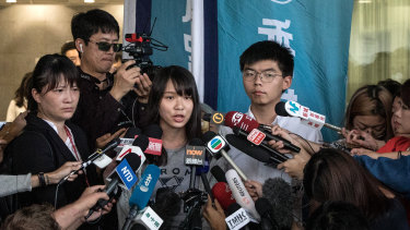 Hong Kong pro-democracy activists Agnes Chow and Joshua Wong speak to the media after being arrested and released on bail.