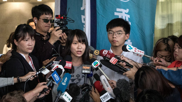 Hong Kong pro-democracy activists Agnes Chow and Joshua Wong speak to the media after being arrested and released on bail.