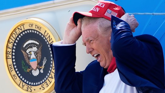 President Donald Trump holds his hat in the wind as he disembarked Air Force One last week.