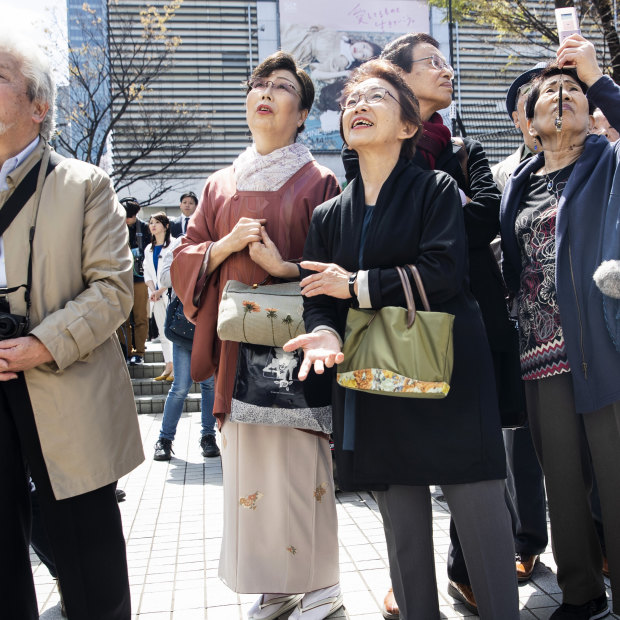 Pedestrians in Tokyo watch as the name of the new era is unveiled on April 1.