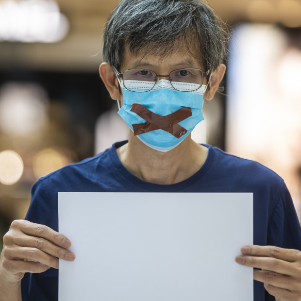 Protesters have been warned they may be in breach of national security laws for raising blank pieces of paper, as this demonstrator did on June 6. 