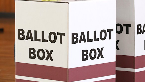 An election official sanitizes voting areas at a polling booth.