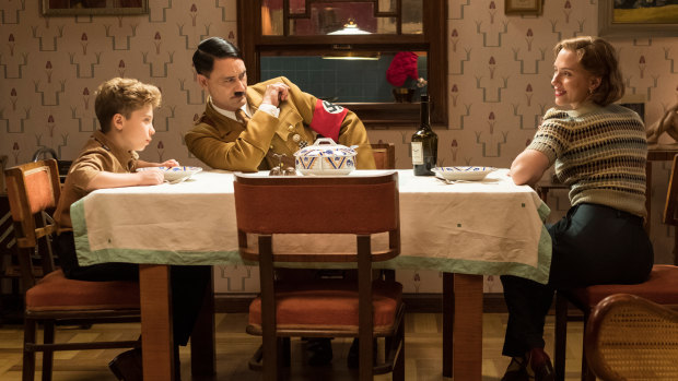  Jojo (Roman Griffin Davis) has dinner with his imaginary friend Adolf (writer/director Taika Waititi), and his mother, Rosie (Scarlett Johansson). 