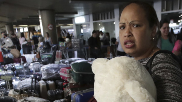 A Cuban doctor clutching a teddy bear prepares to depart the airport with her colleagues in Brasilia, after they were recalled by the Cuban government.