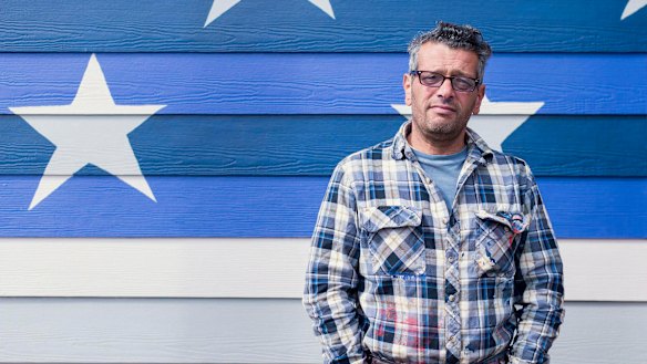 Scott LoBaido in front of an American flag he painted in Ketchikan, Alaska.