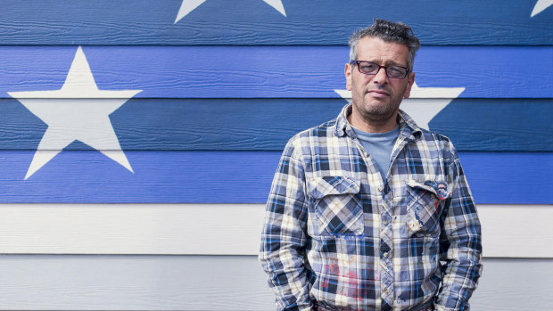 Scott LoBaido in front of an American flag he painted in Ketchikan, Alaska.