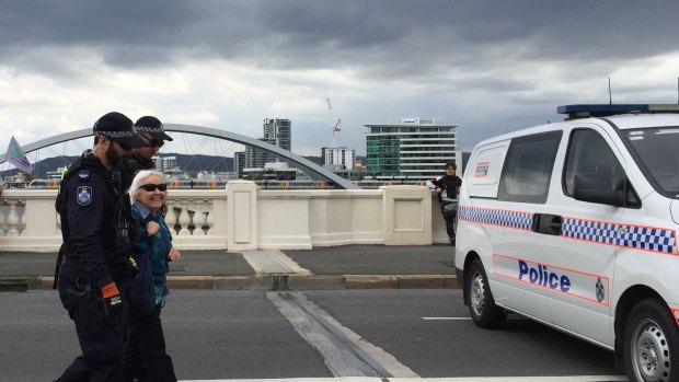 An elderly climate activist is arrested on South Brisbane's William Jolly Bridge on Friday.
