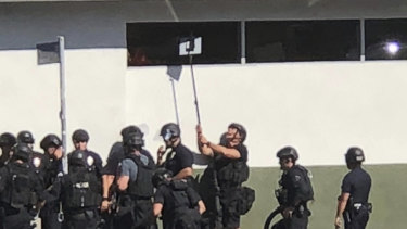 Police officers use a mirror to see inside a Trader Joe's store in the Silver Lake neighbourhood of Los Angeles on Saturday.