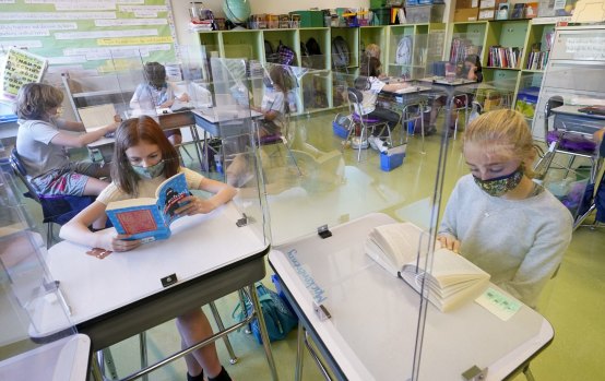 Students wearing face masks are separated by plexiglass at a school in New York state. 