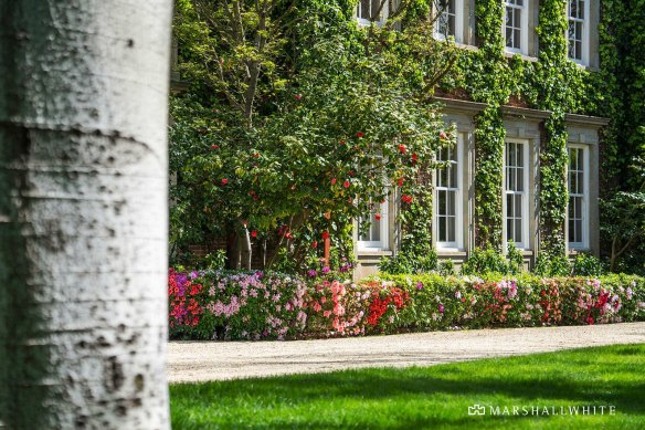 The house is set in manicured gardens.