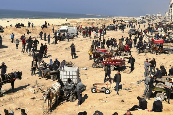 Palestinians wait for humanitarian aid on a beachfront in Gaza City.