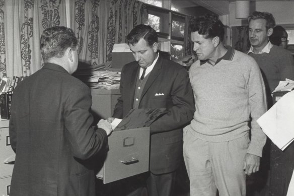 Journalist Maxwell Newton, third from left, looks on as police search his home and office in 1969. 