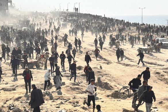 Palestinians wait for humanitarian aid on a beachfront in Gaza City.