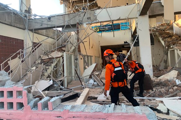 In this photo released by the Indonesian National Search and Rescue Agency (BASARNAS), rescuers search for victims at a damaged building following an earthquake in Maumere, East Nusa Tenggara Province, Indonesia.