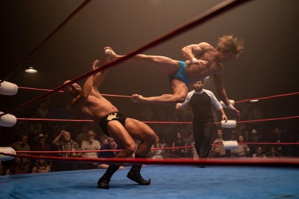 Zac Efron (right), as Kevin Von Erich, launches himself at an opponent in the wrestling ring in The Iron Claw. 