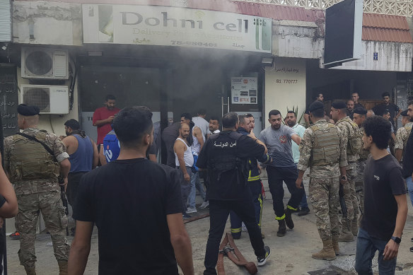 Soldiers and firefighters gather outside a mobile shop after what is believed to be the result of a walkie-talkie exploding inside it, in the southern port city of Sidon, Lebanon.