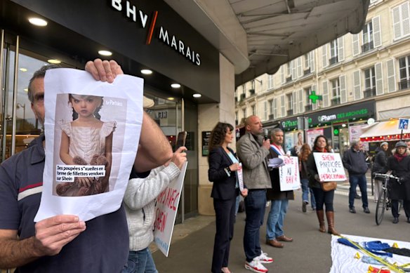 A protester holds a picture of a childlike sex doll outside the new Shein store at BHV Marais in Paris.