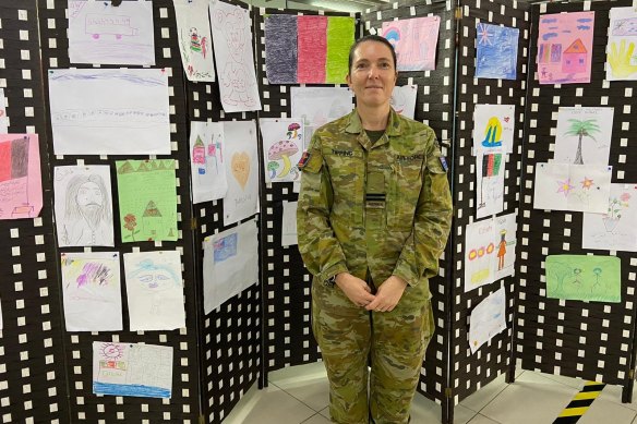 Flight Lieutenant Danielle Tipping stands against a wall of pictures drawn by refugee children airlifted from Kabul.
