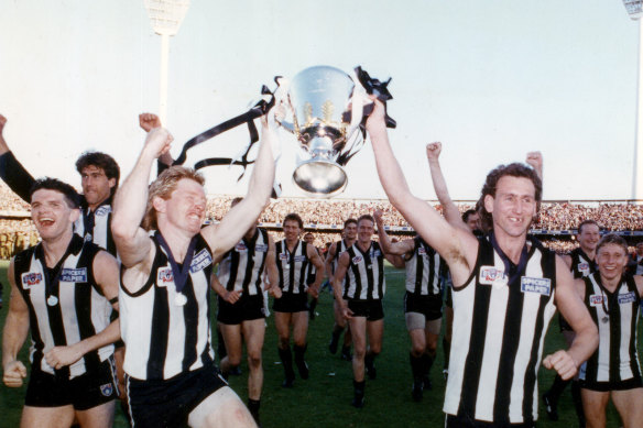Collingwood players celebrate with the premiership trophy.