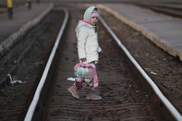 A young refugee girl fleeing Ukraine walks across the tracks as she arrives at the border train station of Zahony on March 08, 2022 in Zahony, Hungary. 