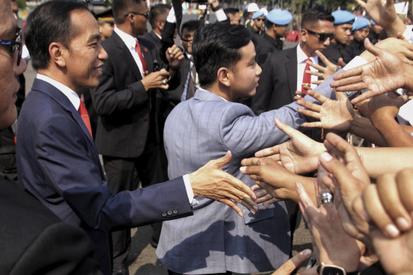Indonesian President Joko Widodo (left) and his son Gibran Rakabuming Raka greet supporters in 2019.