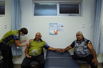 Dr Heather McKenzie (left) administers the COVID-19 vaccination to Darryl Wright (centre) moments after Ivan Wellington (right) received his shot at Tharawal 
Aboriginal Corporation’s Medical Centre in Airds.