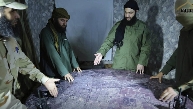 Abu Mohammed al-Golani of the militant Levant Liberation Committee and the leader of Syria's al-Qaeda affiliate, second right, discusses battlefield details with field commanders over a map, in Aleppo, Syria. Golani has vowed to fight on in Idlib province, in the face of a possible government offensive.