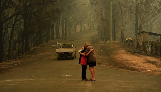 Residents comfort each other in Nelligen, west of Batemans Bay, on January 1, after fire destroyed homes.