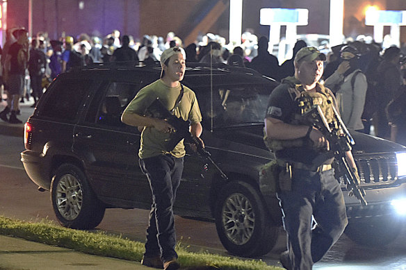 Kyle Rittenhouse, left, with backwards cap, walks along Sheridan Road in Kenosha, Wisconsin. Prosecutors have charged the 17-year-old with the killing of two protesters and the wounding of a third.