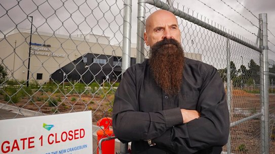 Hume City Council councillor Jim Overend in front of the Craigieburn Community Hospital which was built months ago but still isn’t open for use.