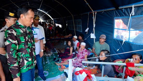 Indonesian President Joko Widodo talks with tsunami survivors in a temporary shelter in Palu on Sunday.