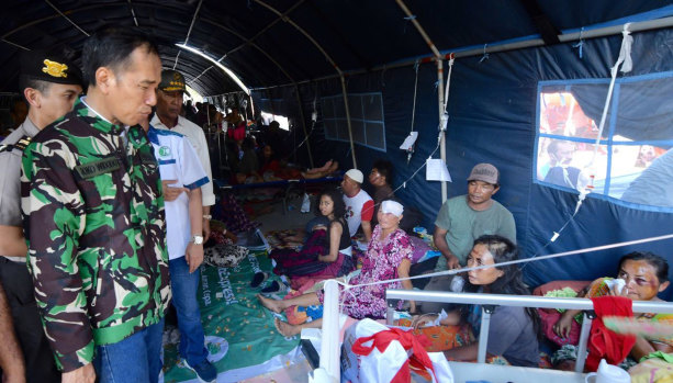 Indonesian President Joko Widodo talks with tsunami survivors in a temporary shelter in Palu on Sunday.