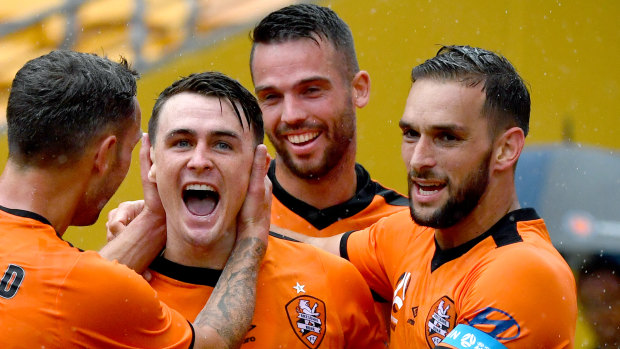 Dylan Wenzel-Halls (centre) of the Roar celebrates scoring a goal with Scott McDonald (left) and Jack Hingert (right).