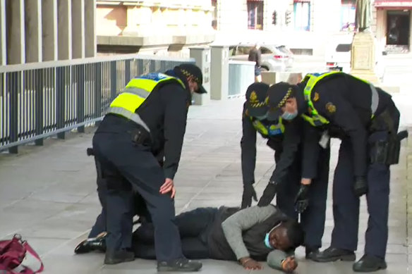 Protective Service Officers attend to a man who interrupted Premier Daniel Andrews’ press conference.