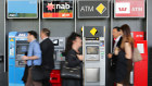 People walking past a row of ATMs belonging to the four big banks.