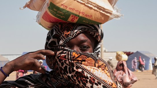 A Sudanese woman displaced from El Fasher collects food aid at El Afadh refugee camp.