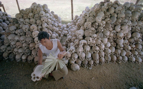 A man cleans a skull near a mass grave at the Chaung Ek torture camp run by the Khmer Rouge, in this undated photo.  