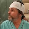 Keith Davis (centre) is whisked away and prevented from talking to reporters at Samitivej Srinakarin Hospital in Bangkok, Thailand.