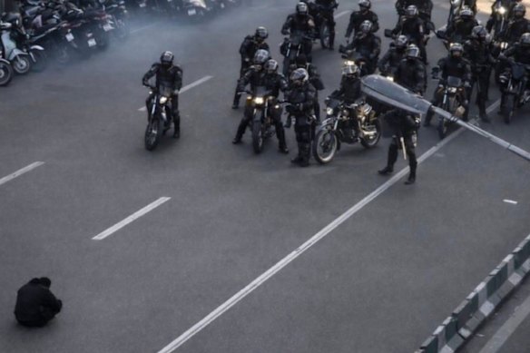 A still from video reportedly showing a protester sitting in the middle of a Tehran street, refusing to move, as security forces on motorcycles advance before beating him. The image has been likened to China’s Tiananmen Square “Tank Man”.