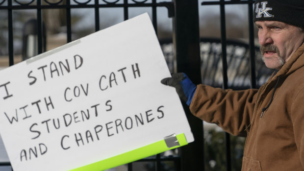 Firestorm: A man places a sign showing support for the students of Covington Catholic High School.