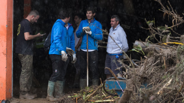 Rafael Nadal (centre) works with residents to clear from homes after flooding in Majorca.