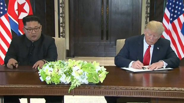 Donald Trump and Kim Jong-un sign statements after their Singapore meeting.