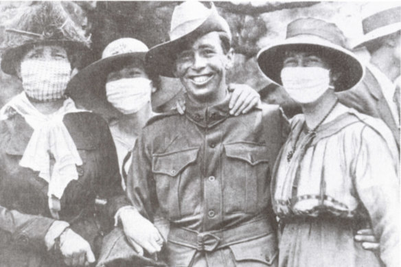 A returned soldier poses with women in anti-flu masks, 1919.