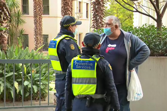 Protective Service Officers chat to a man who was complaining to Health Minister Martin Foley about not being granted a travel exemption.