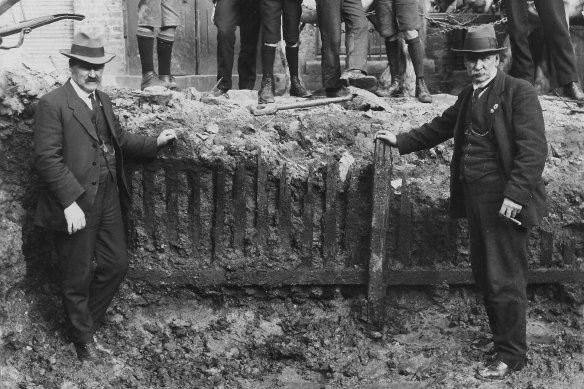 Men pose in front of the picket fence unearthed in the early 1920s during excavation work for the Capitol Theatre on Swanston Street.